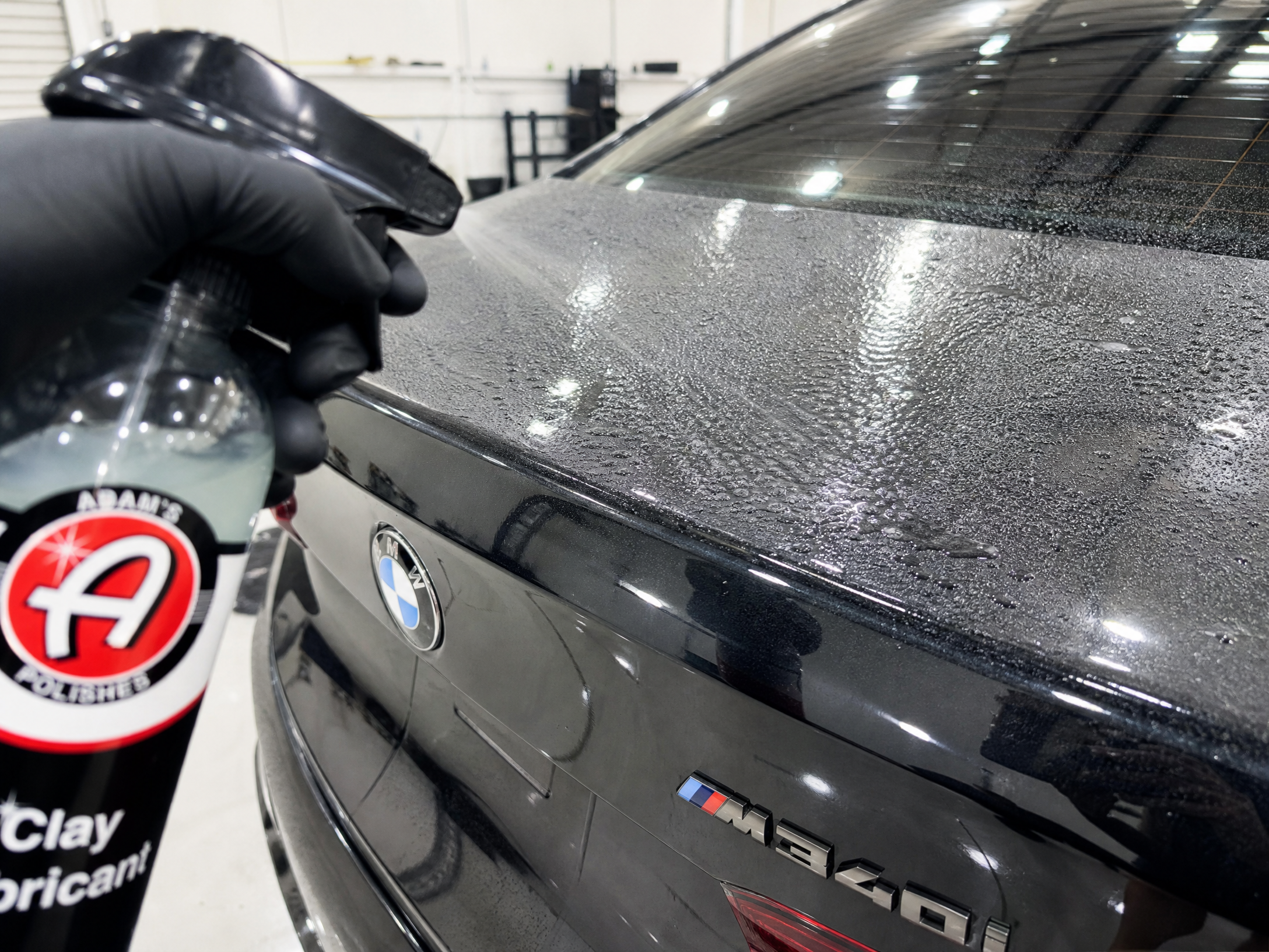 Detailer applying clay lubricant to a car panel