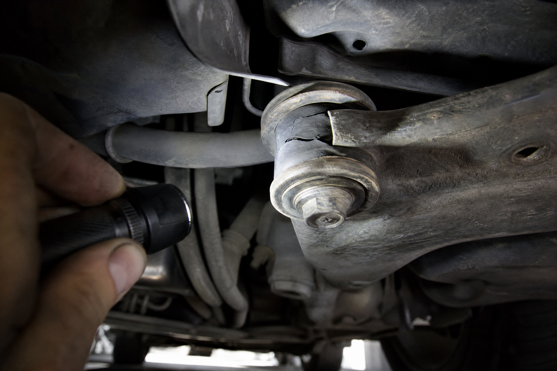 Mechanic inspecting a raised car's undercarriage with a work light and mirror