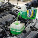 car owner topping off green coolant to coolant reservoir